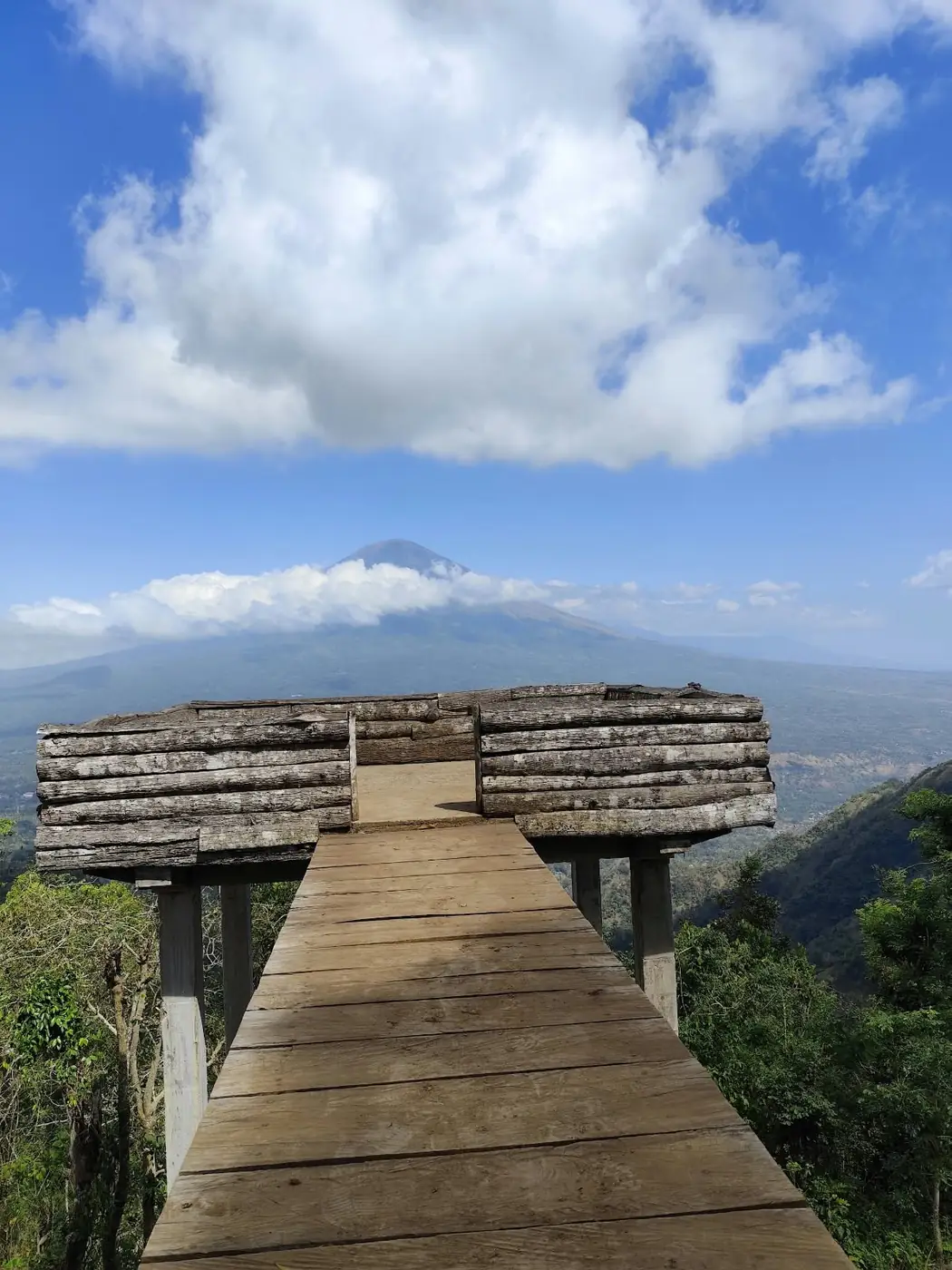 Wooden walkway leading to a viewpoint with Mount Agung in the distance