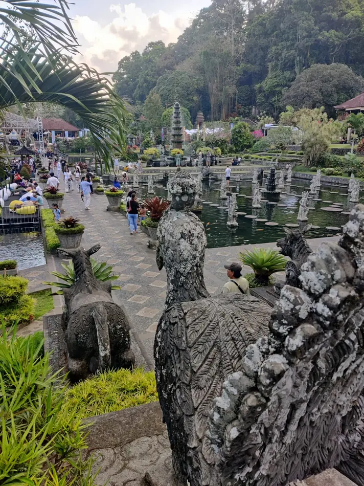 Stone guardian figures above the ponds and eleven-tiered fountain at Tirta Gangga