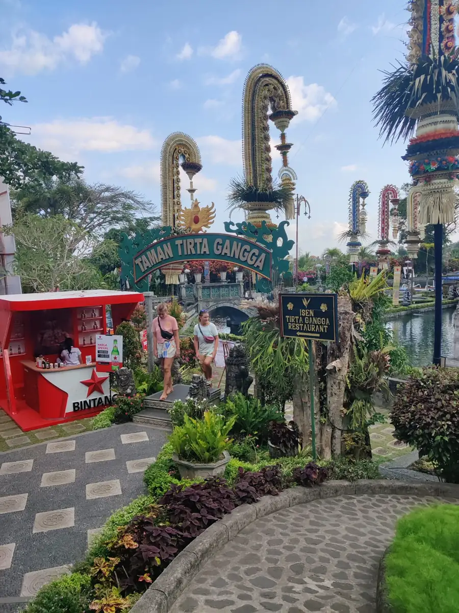 Taman Tirta Gangga entrance archway with penjor poles along the road